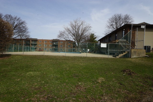 A grassy area in front of a building with a fence.
